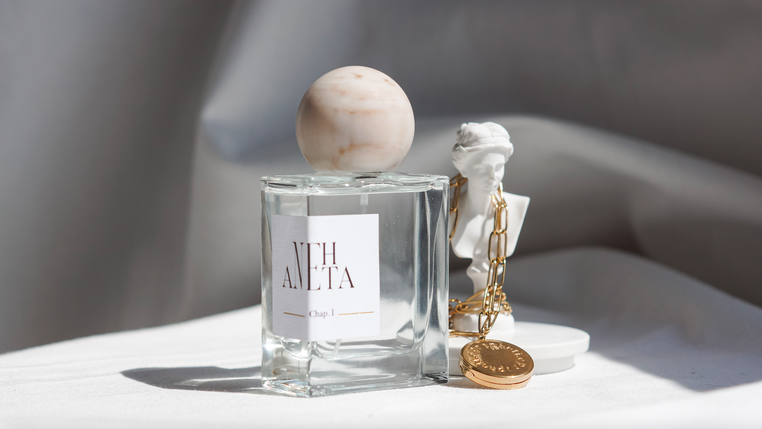 parfum ANEHTA et bijou Propheti.e enroulé sur une statuette