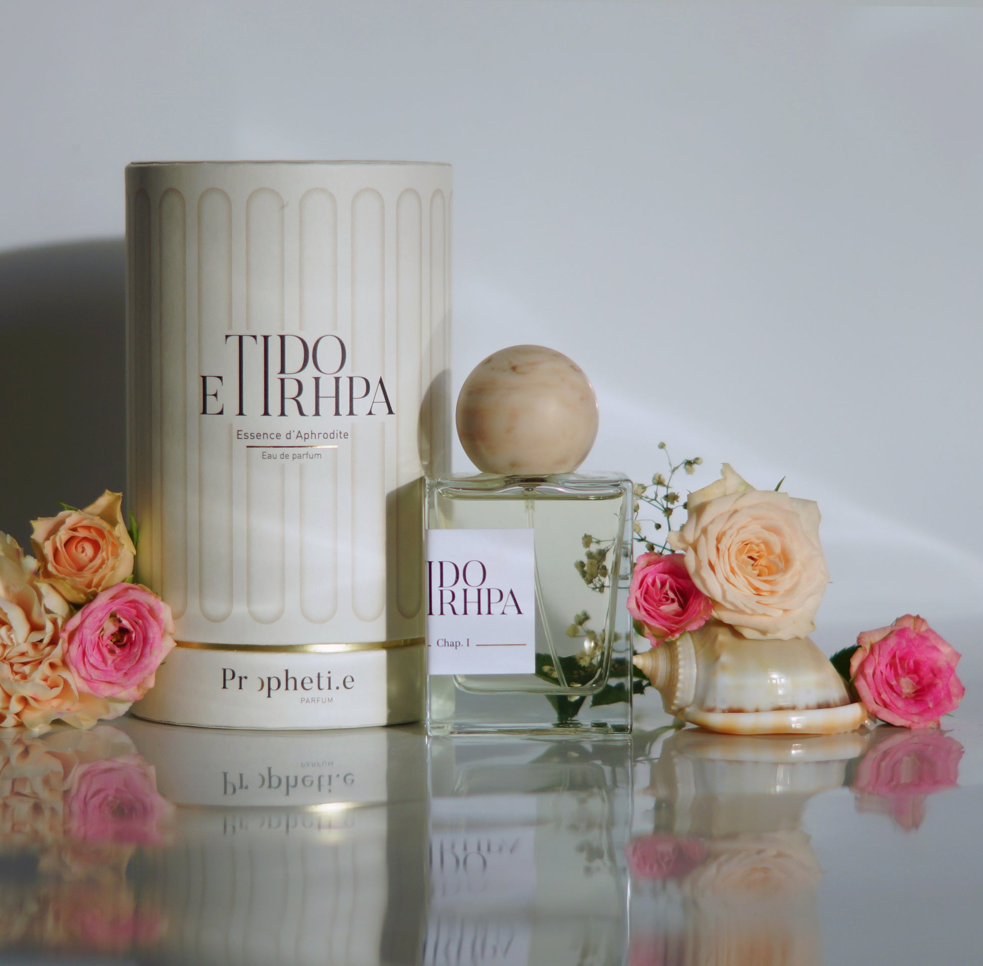 Coffret Anehta avec le parfum à côté avec des roses rose et quelques fleurs coquillages - Vue de face