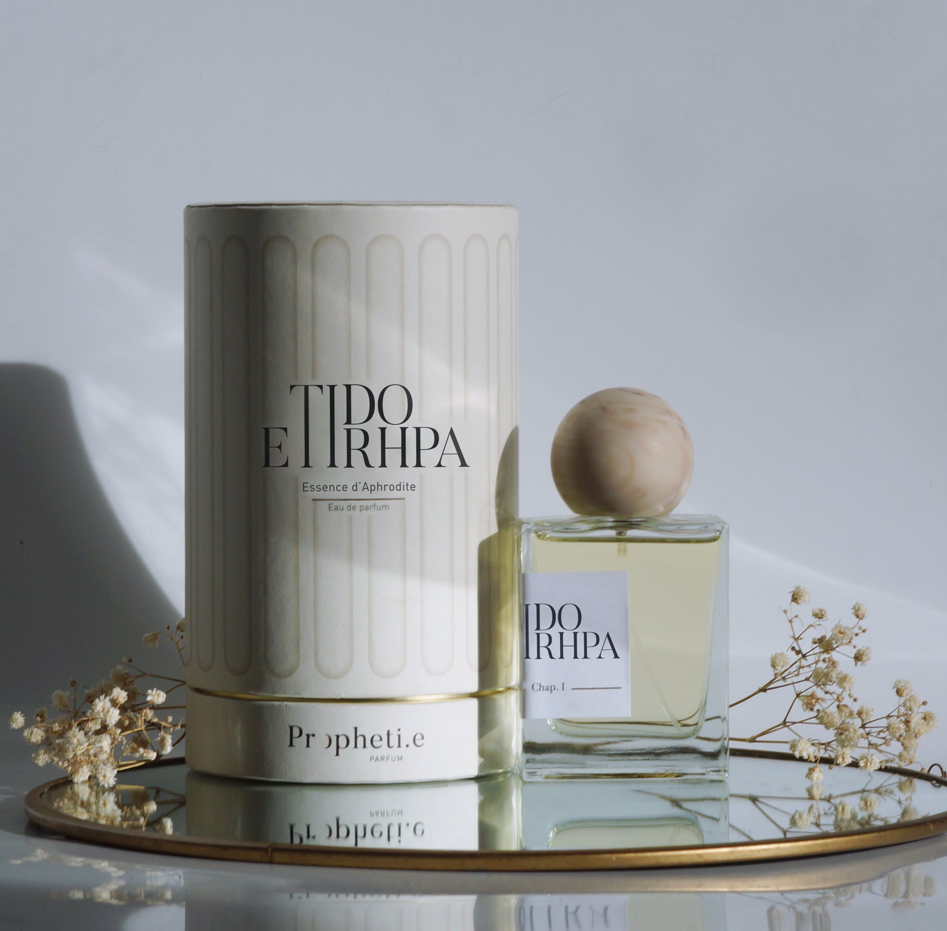 Coffret Etidorhpa avec le parfum à côté posé sur un miroir avec des fleurs séchées - Vue de face