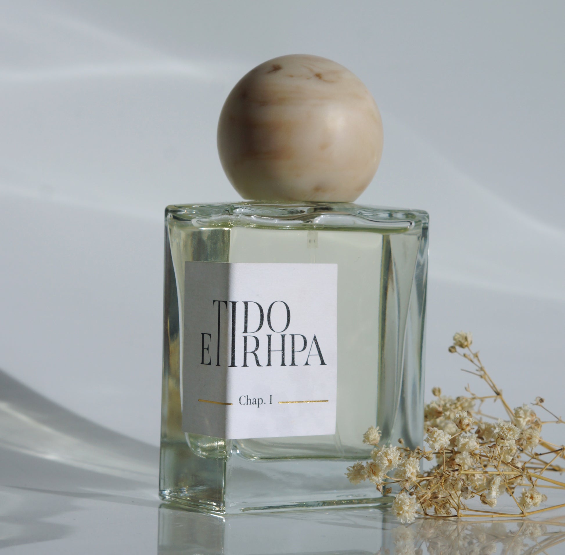 Le parfum Etidorhpa vue de biais avec quelques fleurs séchées.