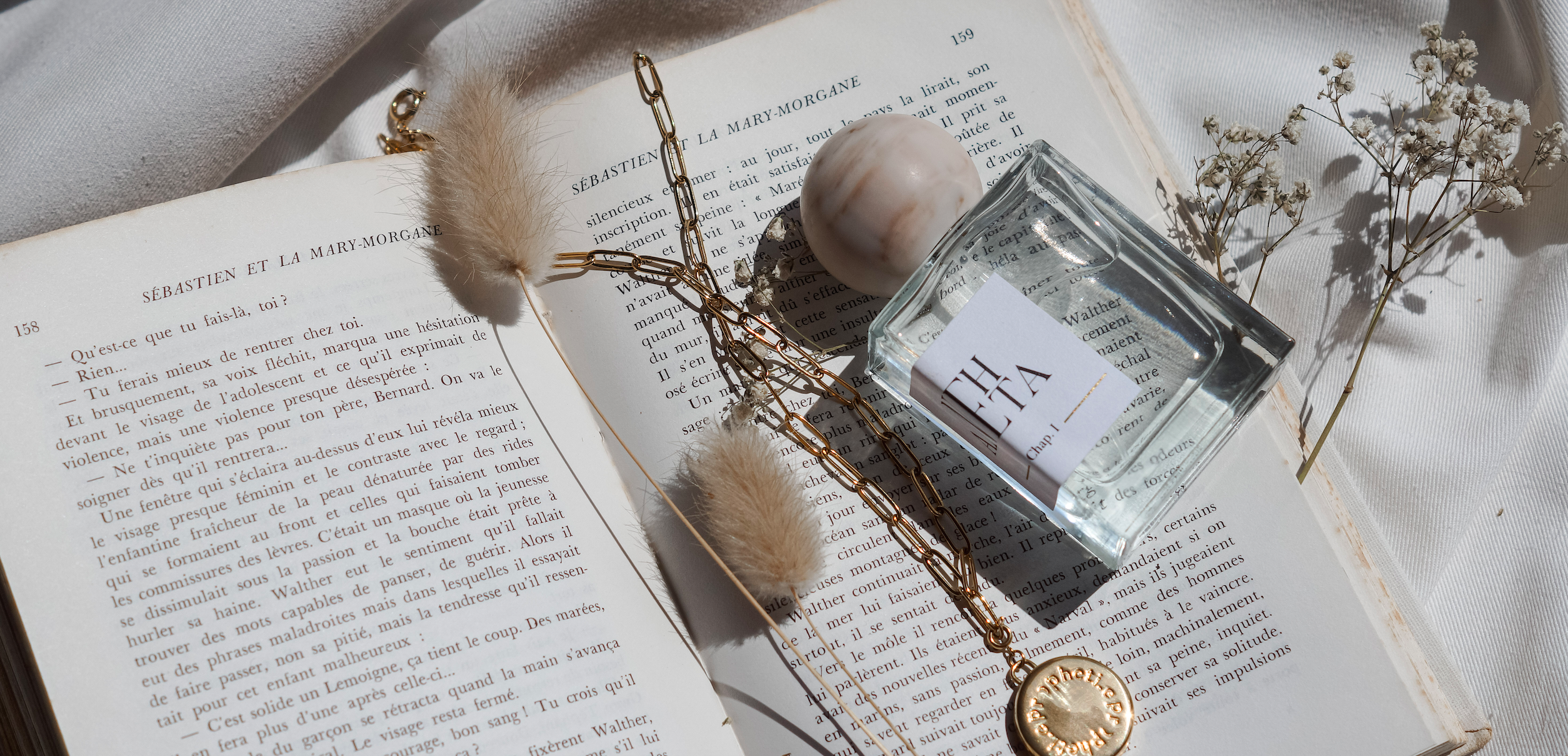 parfum ANEHTA et bijou Propheti.e posés sur un livre