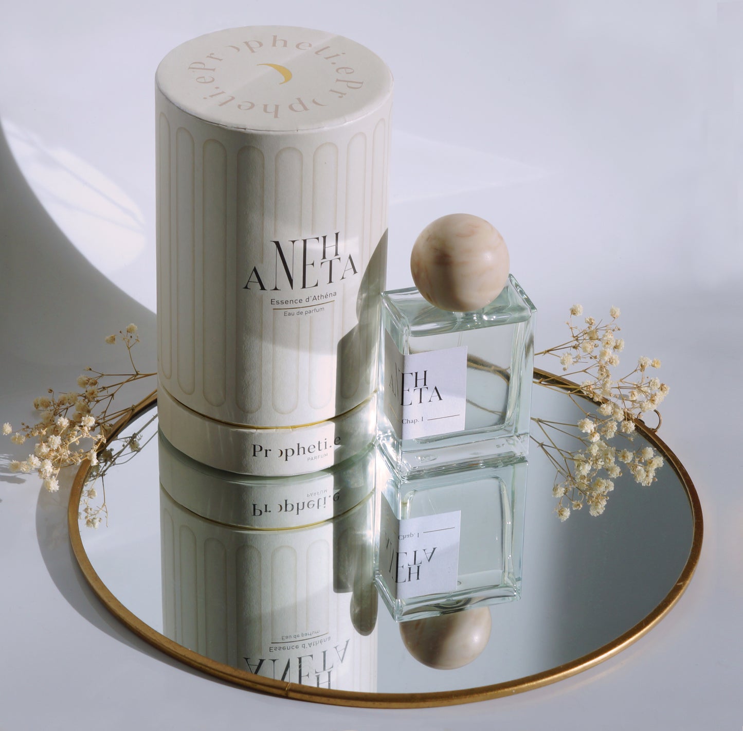 Coffret Anehta avec le parfum à côté posé sur un miroir avec des fleurs séchées - vue du dessus