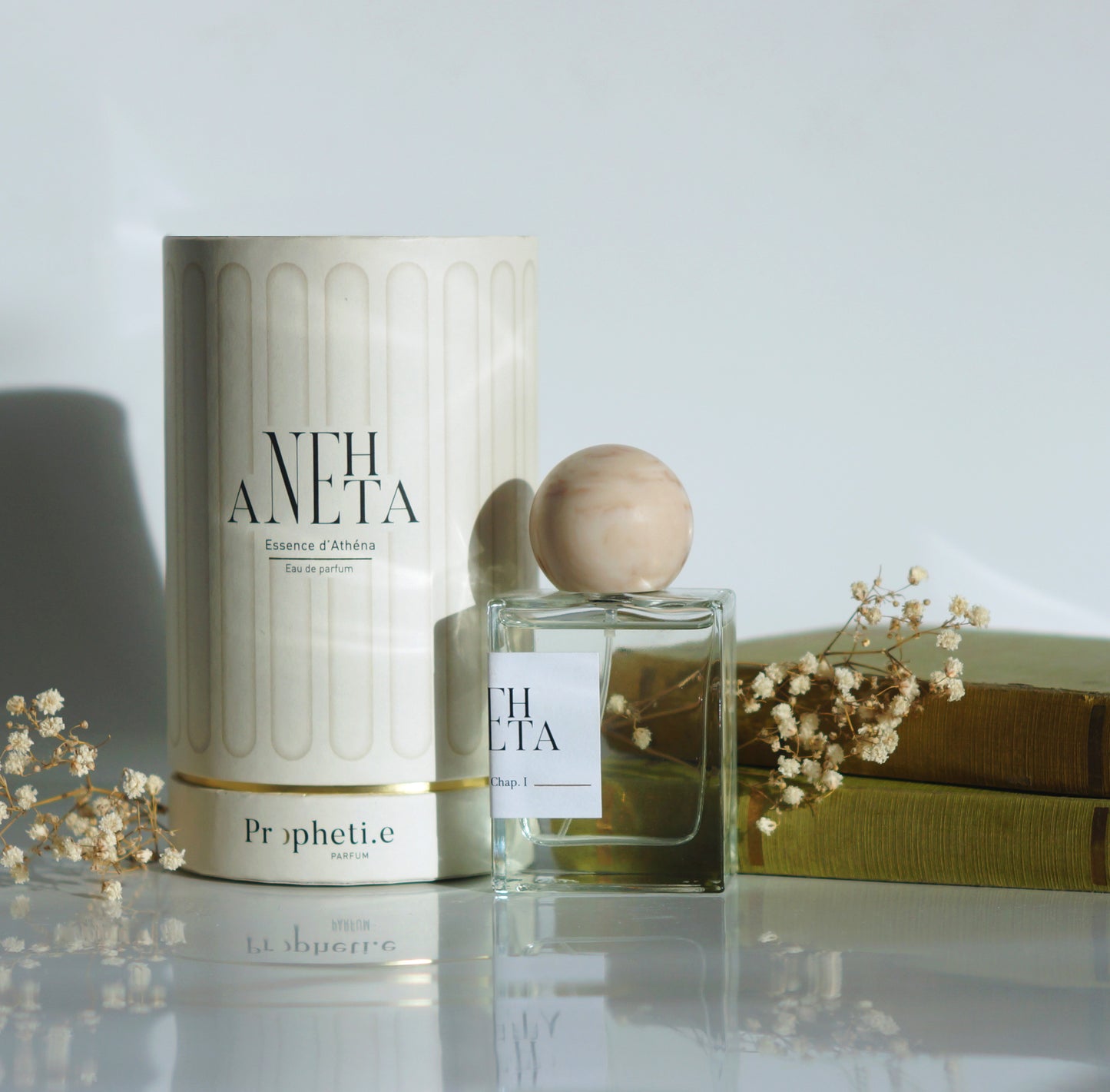 Coffret Anehta avec le parfum à côté avec des livres et quelques fleurs séchées - Vue de face