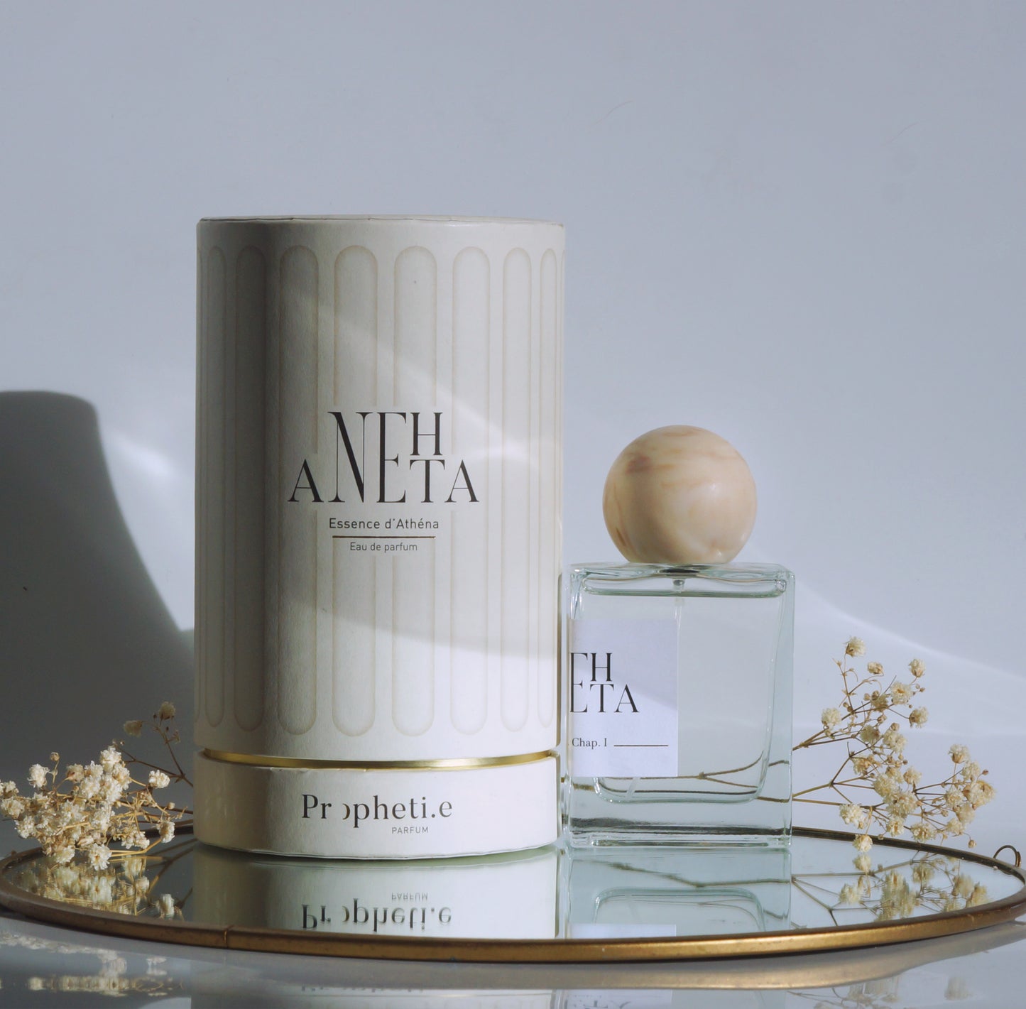 Coffret Anehta avec le parfum à côté posé sur un miroir avec des fleurs séchées - vue de face