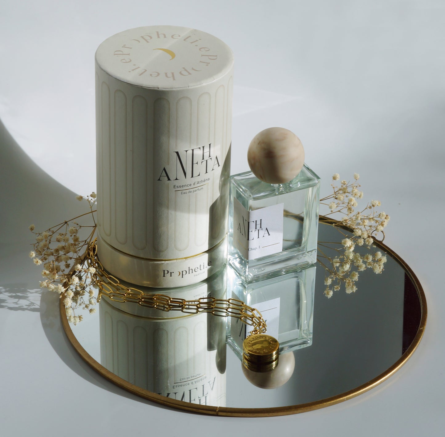 Coffret Anehta avec le parfum à côté posé sur un miroir avec des fleurs séchées et le bijou face Propheti.e - Vue de dessus