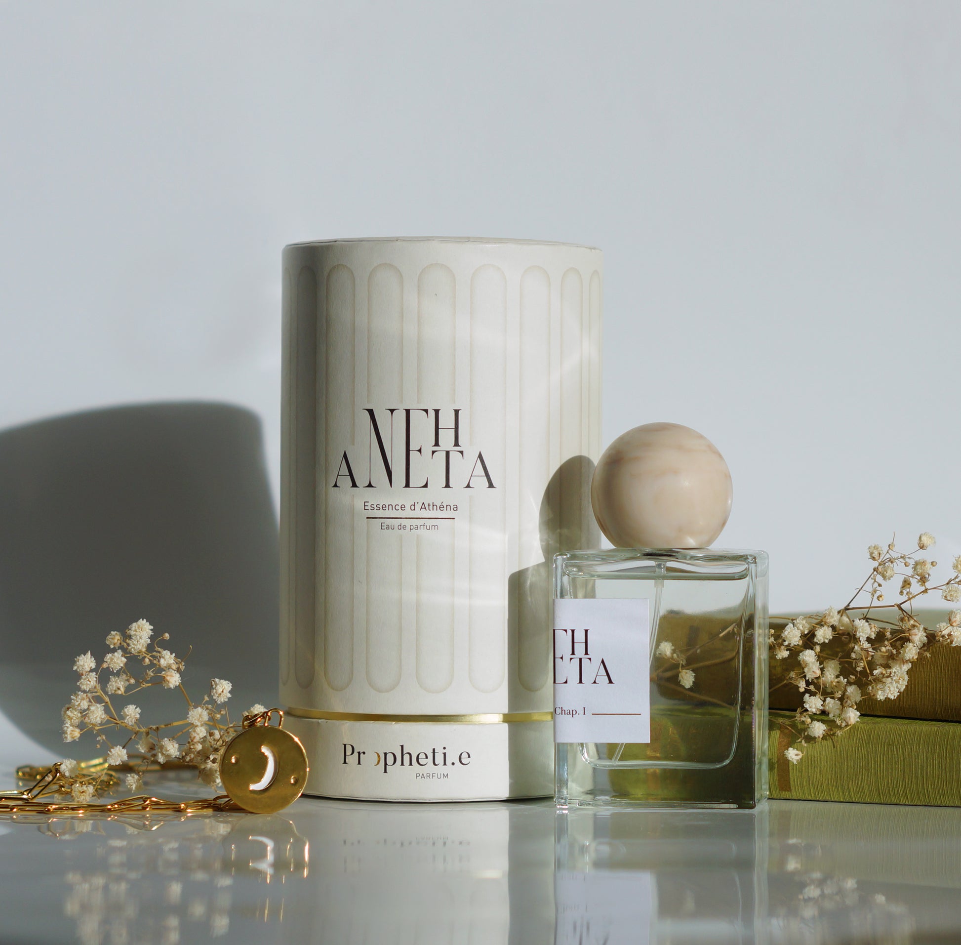 Coffret Anehta avec le parfum à côté avec des livres et quelques fleurs séchées + le bijou face Lune - Vue de face