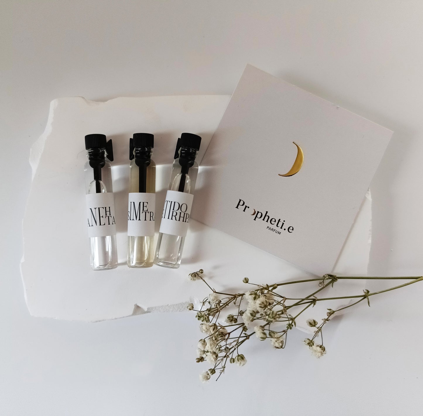 3 Échantillons de parfum 2ml Propheti.e sur une pierre à plat : SIMETRA, ANEHTA et ETIDORHPA avec une carte Propheti.e et une fleur séchée