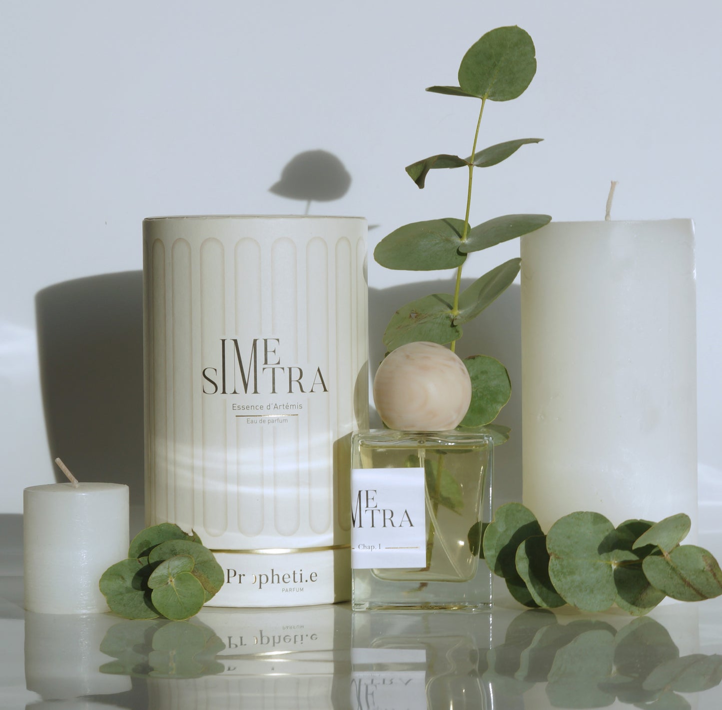 Coffret Simetra avec le parfum à côté avec des branches d'eucalyptus et bougies - Vue de face